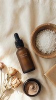 Natural organic skincare products with serum bottle, sea salt scrub and dried roses on linen fabric for spa wellness and beauty routine.