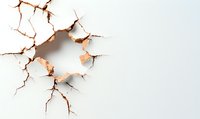 Cracked white wall with hole revealing brown interior, symbolizing breakthrough, damage, or deterioration in construction or design concepts.