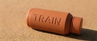 Terracotta whistle with train text engraved on sandy surface, suitable for educational toys, children's products, and vintage-inspired designs.