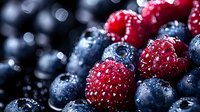 Fresh ripe raspberries and blueberries with water drops on dark background, macro shot showing juicy texture and natural organic freshness.