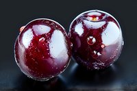 Fresh ripe dark red cherries with water drops on black background, macro photography showing texture and natural gloss of fruit surface.