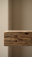 Natural wood beam with rich grain patterns and rustic texture against neutral beige wall background for interior design and construction projects.