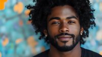 Young African American man with curly hair and beard smiling confidently against colorful bokeh background for lifestyle and portrait photography.