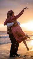 Young couple in traditional folk costumes dancing joyfully on beach at sunset with warm golden light and ocean waves creating romantic atmosphere.