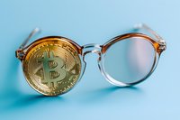 Golden cryptocurrency coin replacing lens in transparent round glasses frame on light blue background, modern financial vision concept.