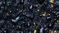 Dramatic black water drops on dark surface with golden particles scattered around creating contrast between wet glossy texture and metallic sparkles.