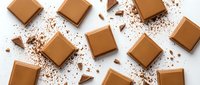 Caramel candies and chocolate pieces scattered on white background, overhead flat lay composition for confectionery, dessert and candy shop designs.