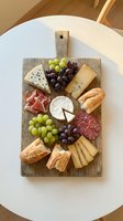 Gourmet cheese and charcuterie board with fresh grapes, artisan bread, cured meats on rustic wooden serving platter for entertaining and appetizers.