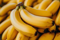 Fresh ripe yellow bananas in bunch close-up macro shot. Natural organic tropical fruits background with selective focus and soft lighting.