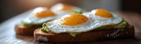 Sunny side up eggs on avocado toast with cracked black pepper, served on rustic wooden board. Close-up panoramic view shows runny yolks and fresh ingredients.