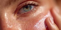 Close-up of woman's blue eye with golden shimmer makeup and glowing skin. Beauty skincare cosmetics concept for luxury products and treatments.