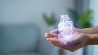 Hands holding glowing anatomical heart model with medical technology overlay in modern healthcare setting for cardiology and wellness concepts.