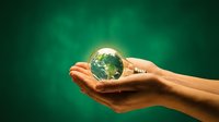 Hands gently holding glowing Earth globe on green background symbolizing environmental protection, sustainability and global care responsibility.