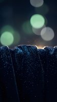 Dark blue fabric with sparkling water droplets and soft bokeh lights creating atmospheric mood for luxury textile and fashion concepts.