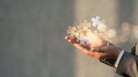 Close-up of hand holding glowing digital puzzle pieces, representing problem-solving, innovation, and business strategy solutions for corporate and technology concepts.