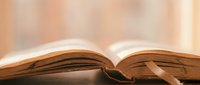 Open book with pages fanned out on wooden surface with warm golden lighting creating peaceful reading atmosphere for education and literature concepts.
