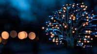 Glowing LED tree installation against dark background with blurred orange bokeh lights creates magical nighttime atmosphere for holiday and festival designs.