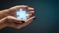 Female hands gently holding glowing puzzle piece symbolizing solution, teamwork and problem-solving in business strategy and innovation concepts.