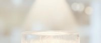 Elegant white marble cylindrical podium on soft bokeh background for luxury product display and cosmetic presentation.