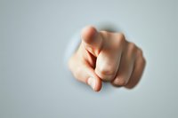 Pointing finger gesture against blurred background shows accusation, blame, or direct selection. Dramatic lighting creates powerful emotional impact.
