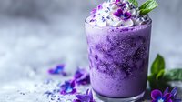 Purple creamy smoothie with edible flowers and mint garnish in glass on light background, selective focus, macro food photography.