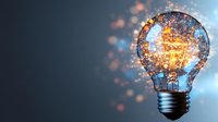Light bulb with glowing filament and sparkling particles on dark background representing innovation, creativity and bright ideas for business concepts.