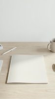 Clean minimal workspace with blank white paper on wooden desk, coffee mug and pen for creative writing, business planning or artistic projects.