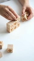 Hands arranging wooden blocks with healthcare symbols including heart, cross and medical icons on white background for wellness concept design.