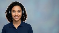 Professional African American woman customer service representative with headset smiling in business attire for corporate communications and support services.