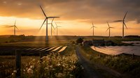 Wind turbines and solar panels generating renewable energy at sunset with golden sky and rural landscape for sustainable power concepts.