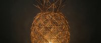 Golden woven pineapple with geometric lattice pattern and crown-like top on dark background, suitable for tropical design projects.