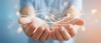 Professional hands presenting flowing digital energy waves with glowing particles and light effects on soft gradient background for technology concepts.