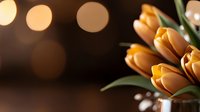 Fresh orange tulips bouquet with warm bokeh lights creating romantic spring atmosphere for home decor and floral arrangements.