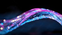 Glowing fiber optic wave with pink and blue light trails against dark background, bokeh effect creates magical atmosphere for technology concepts.