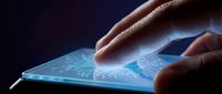 Hands touching futuristic holographic interface on tablet screen with glowing blue digital elements and data visualization in dark environment.