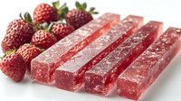 Fresh strawberry fruit leather strips with whole berries on white background, healthy snack food for natural organic nutrition and diet concepts.