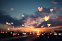 Romantic sunset cityscape with floating heart shapes and bokeh lights creating dreamy atmosphere for love and Valentine's Day concepts.