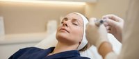 Middle-aged Caucasian woman receiving professional facial injection treatment at modern cosmetic clinic for anti-aging skincare procedure.