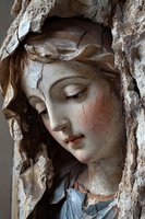 Ancient religious sculpture with cracked surface showing weathered female figure emerging from rough stone, suitable for art history publications.