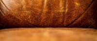 Brown leather texture close-up with natural grain patterns and warm lighting for luxury product backgrounds and interior design projects.