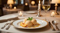Elegant vanilla ice cream dessert with fresh peach slices and mint garnish served on white plate in upscale restaurant setting with wine glass and candlelight.