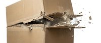 Cardboard box with jagged hole torn through kraft paper revealing interior, scattered debris and torn edges, suitable for packaging, shipping, damage, and delivery concepts.