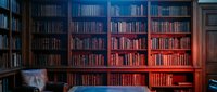 Cozy home library with floor-to-ceiling bookshelves filled with books, warm ambient lighting creating reading atmosphere for study and relaxation.
