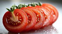 Fresh sliced tomato arranged in a row showing juicy red interior with seeds and pulp on white surface with water droplets. Perfect for food photography.