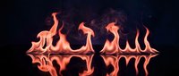 Dancing flames with perfect mirror reflection on dark water surface creating symmetrical fire pattern for dramatic backgrounds and energy concepts.