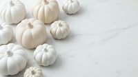 White pumpkins arranged on marble surface for autumn decoration and seasonal design projects with copy space for text.