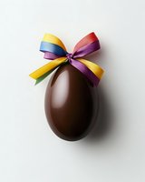 Chocolate Easter egg with colorful ribbon bow on white background, festive holiday treat for spring celebration.