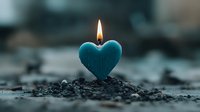 Burning heart-shaped turquoise candle on dark soil background with soft bokeh effect, creating romantic and contemplative atmosphere for spiritual practices.
