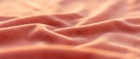 Soft pink coral fabric with flowing waves and gentle folds creating elegant textile texture for fashion and interior design projects.