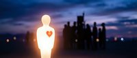 Glowing human figure with illuminated heart symbol standing against urban skyline at dusk, representing love, compassion, and connection in city environment.